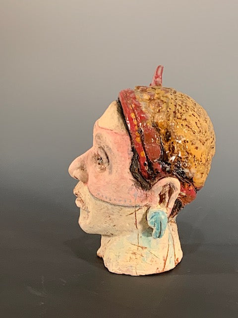 Ceramic sculpture of head with red bow