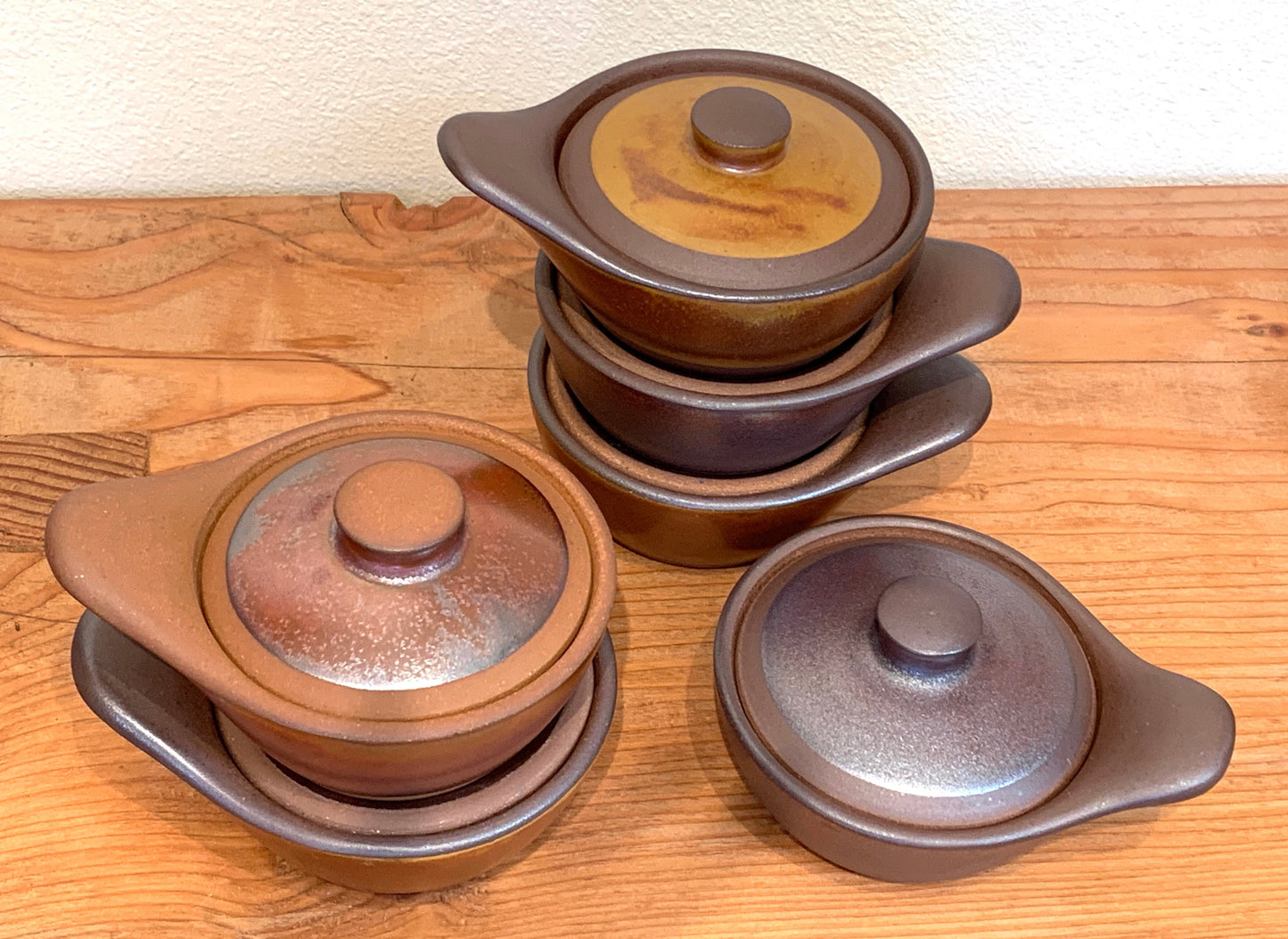 Set of ceramic pots with lids on a wooden surface