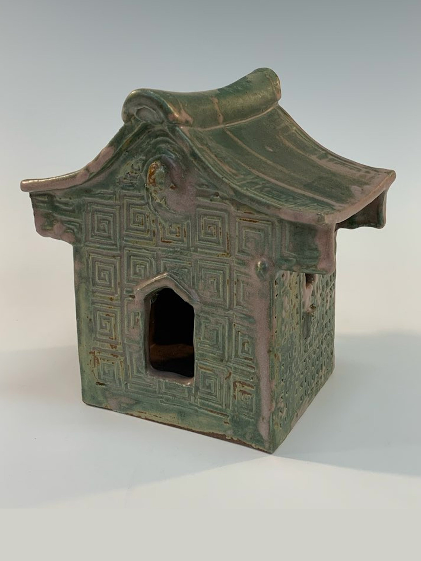Green ceramic house with geometric patterns on a white background