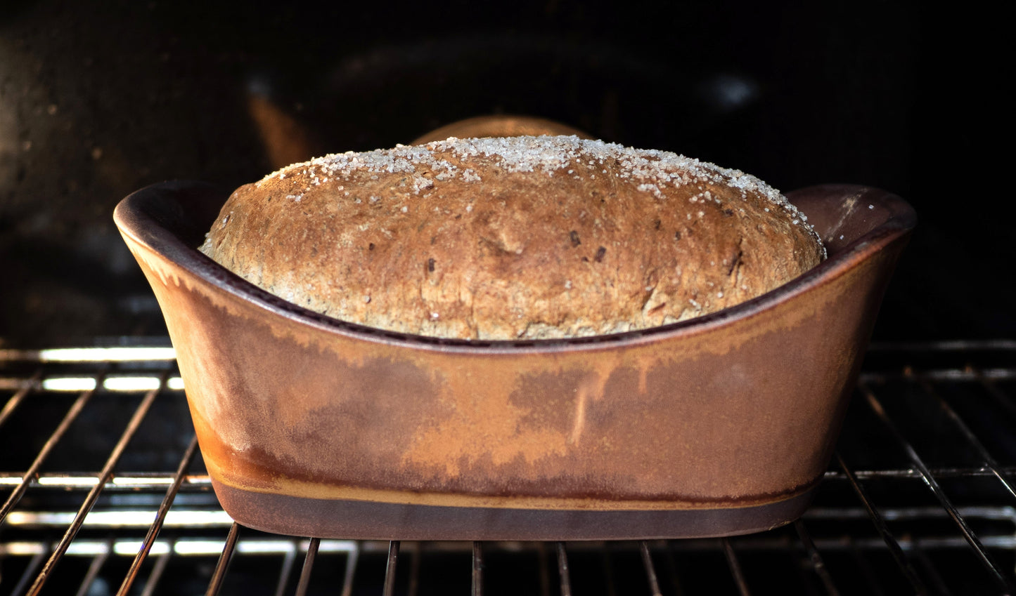 Loaf of bread in a ceramic baking dish inside an oven