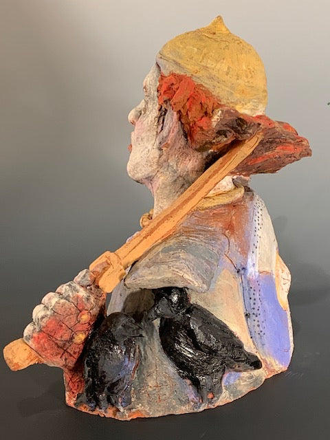 Ceramic bust with colorful face and clothing on a plain background