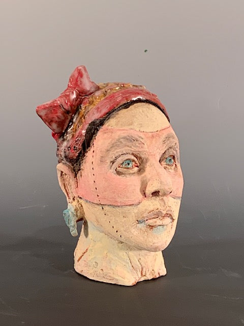 Ceramic sculpture of head with red bow