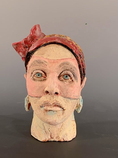 Ceramic sculpture of head with red bow