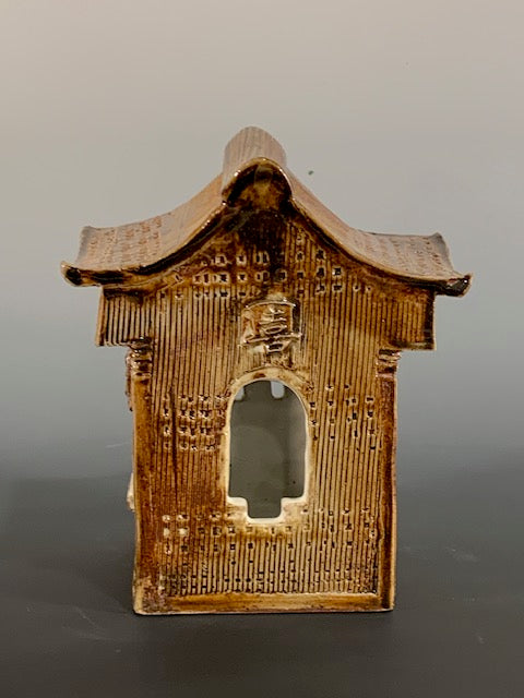 Brown ceramic house with textured surface on a gray background