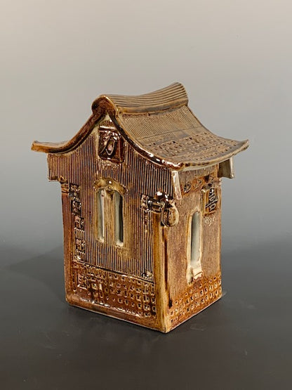 Brown ceramic house with textured surface on a gray background