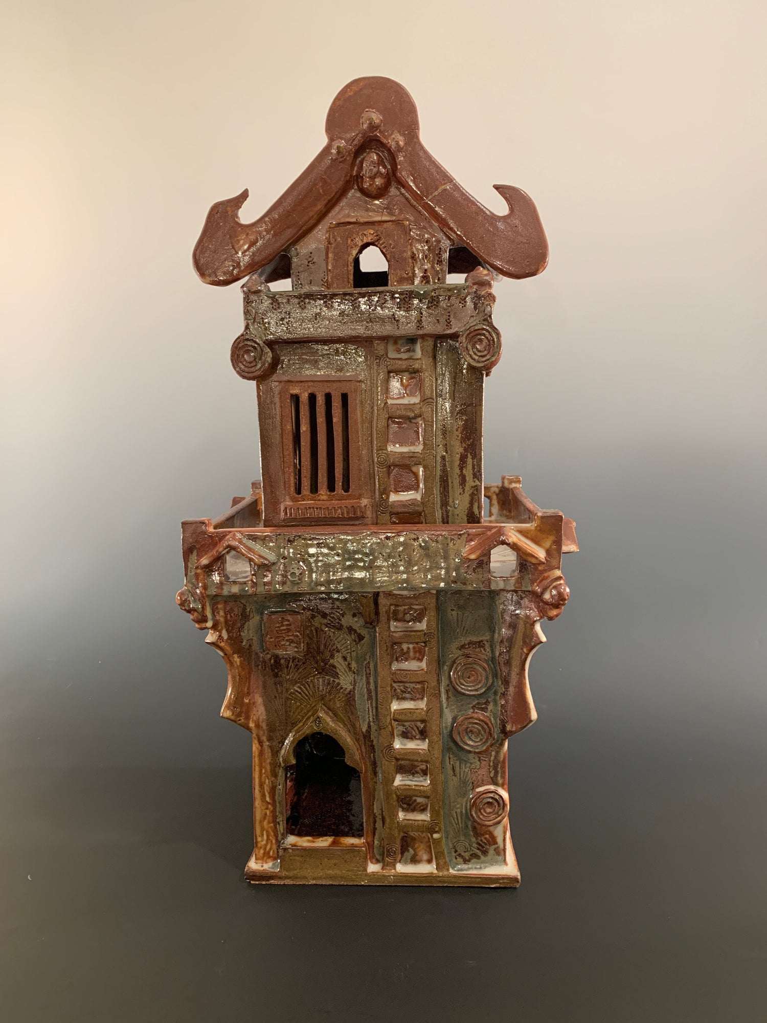 Decorative ceramic house with intricate design on a gradient background