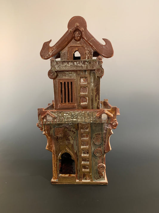 Decorative ceramic house with intricate design on a gradient background