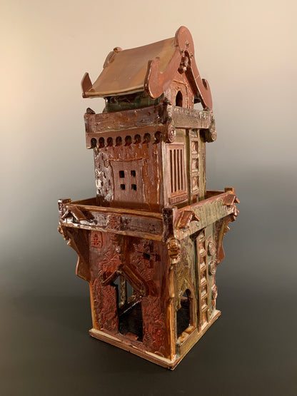 Decorative ceramic house with intricate design on a gradient background