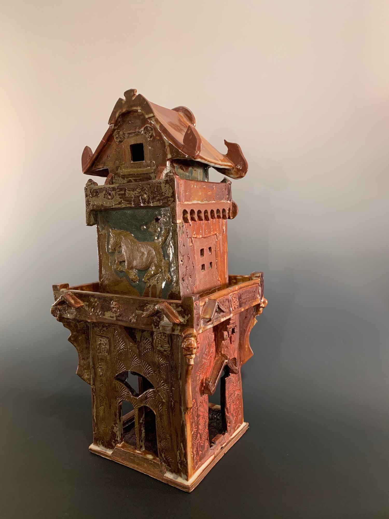 Decorative ceramic house with intricate design on a gradient background