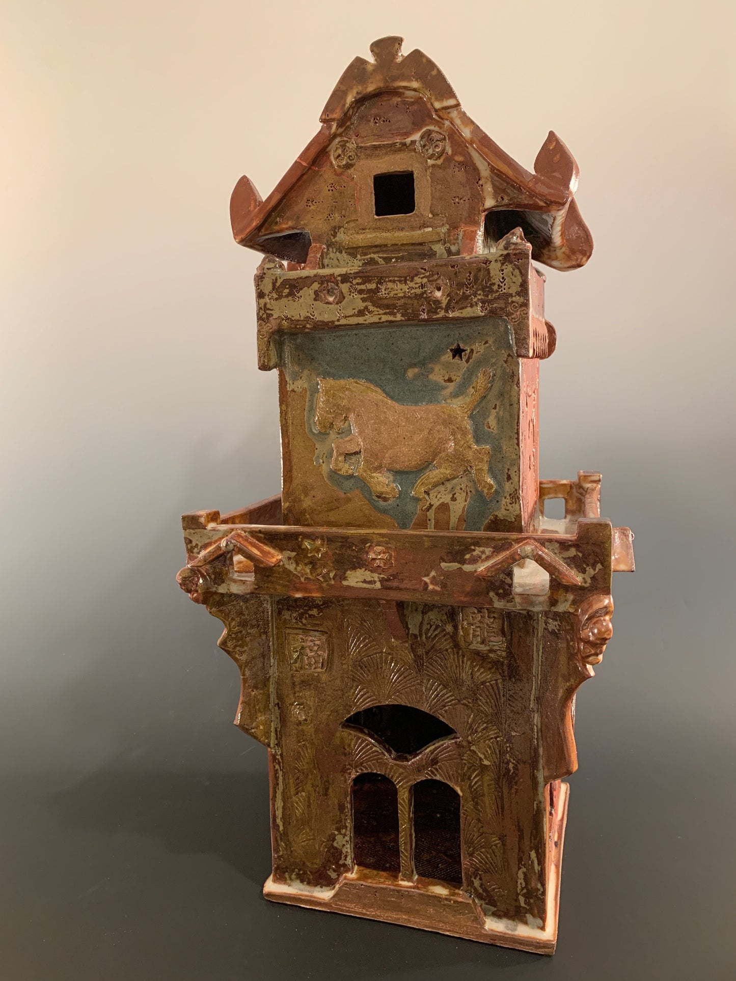 Decorative ceramic house with intricate design on a gradient background