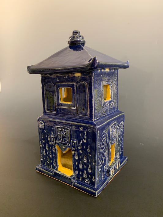 Blue ceramic house with intricate designs on a gray background
