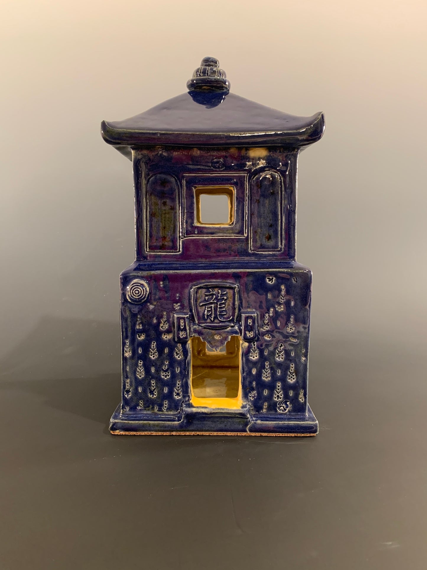 Blue ceramic house with intricate designs on a gray background