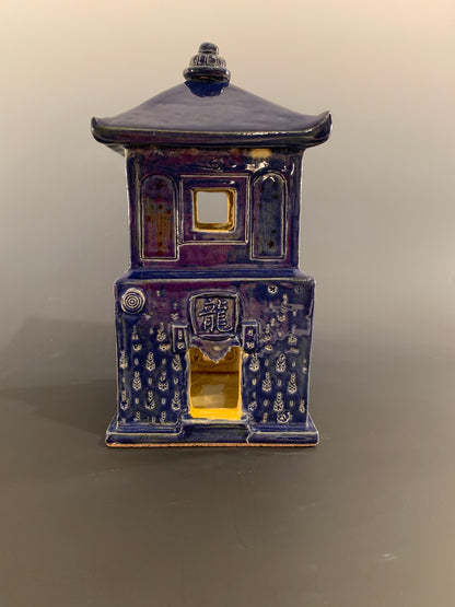 Blue ceramic house with intricate designs on a gray background
