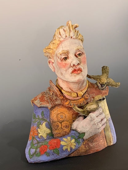 Colorful ceramic sculpture of a face with floral patterns on a gray background
