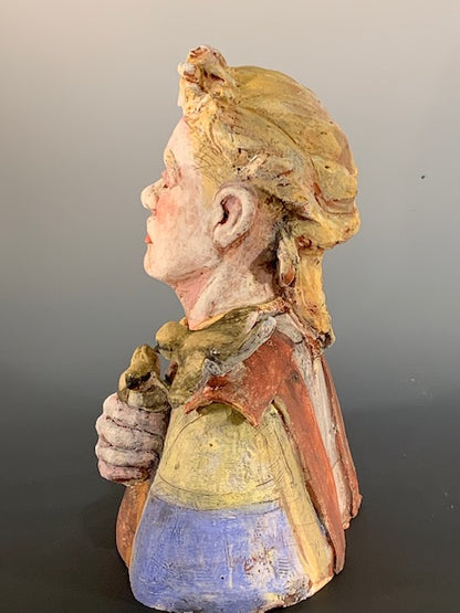 Colorful ceramic sculpture of a face with floral patterns on a gray background
