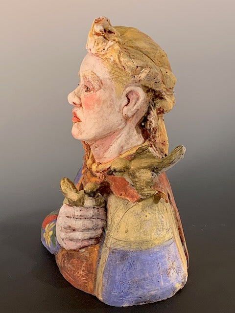 Colorful ceramic sculpture of a face with floral patterns on a gray background