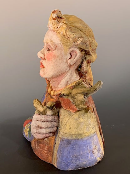 Colorful ceramic sculpture of a face with floral patterns on a gray background