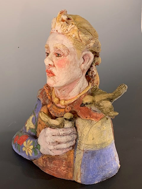 Colorful ceramic sculpture of a face with floral patterns on a gray background