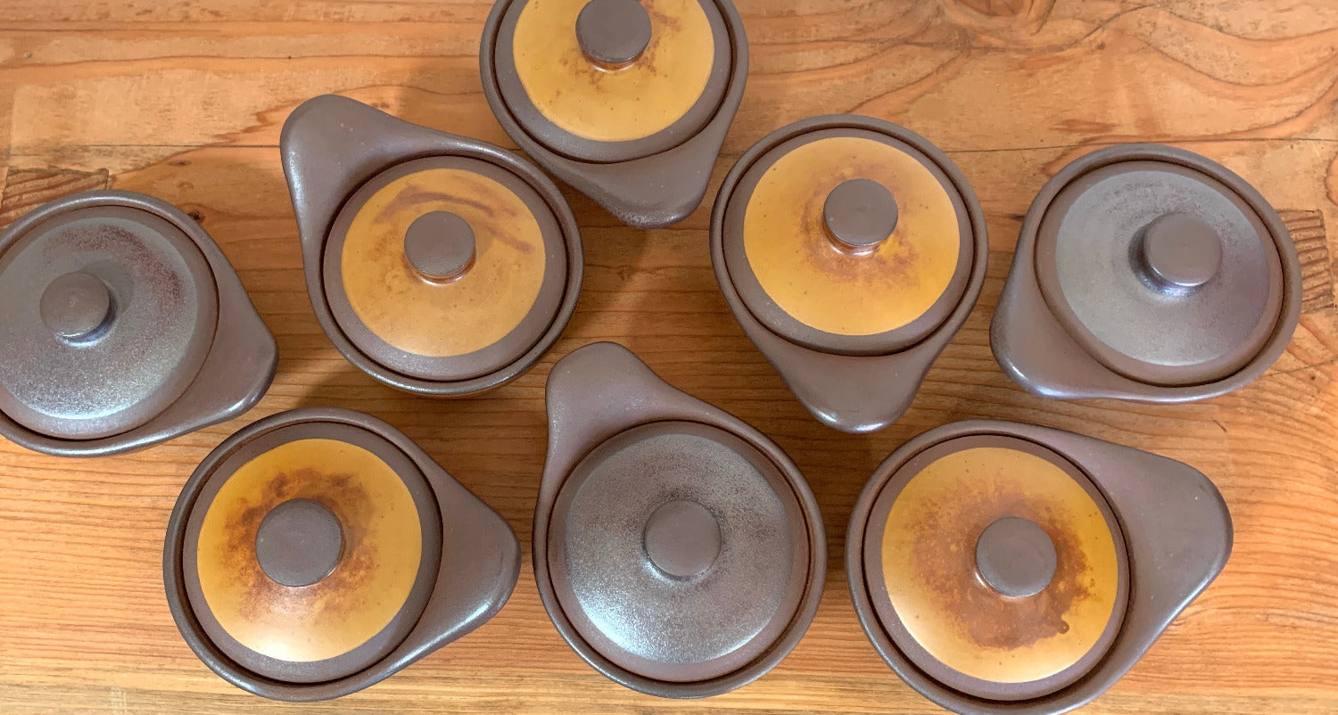 Set of ceramic pots with lids on a wooden surface