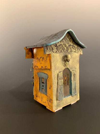 Decorative ceramic house with green and orange colors on a gray background