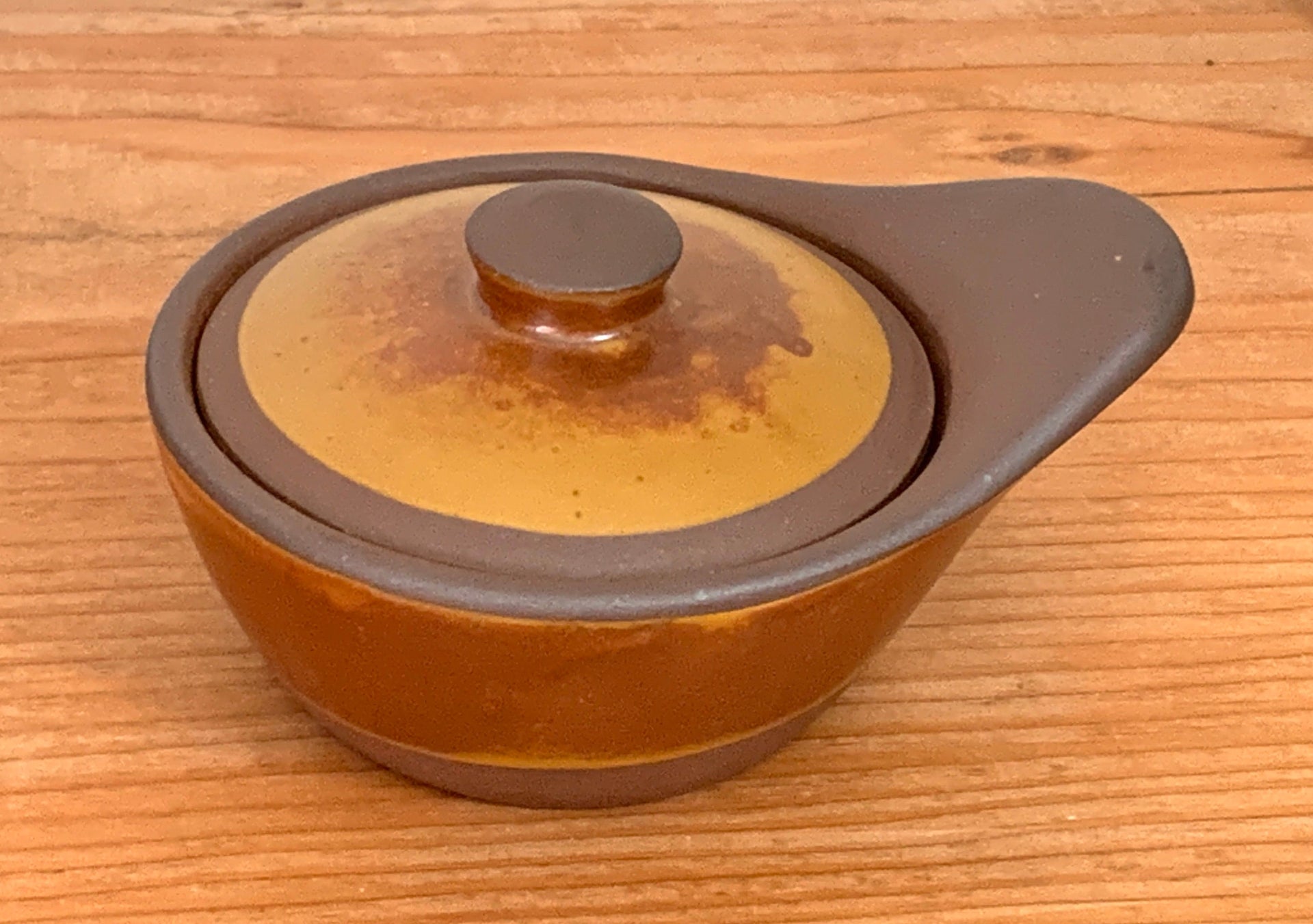 Ceramic pot with a lid on a wooden surface
