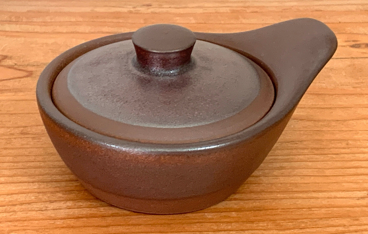 Ceramic pot with lid on a wooden surface