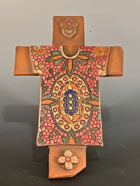 Decorative ceramic cross with intricate patterns on a plain background