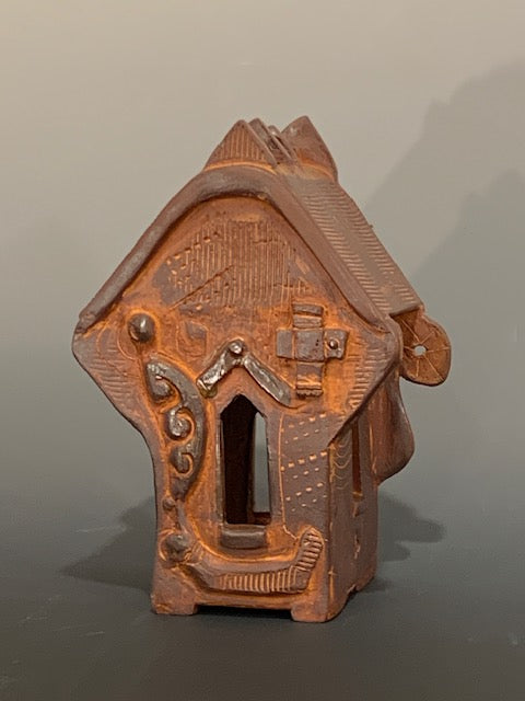 Ceramic decorative house with intricate design on a gray background