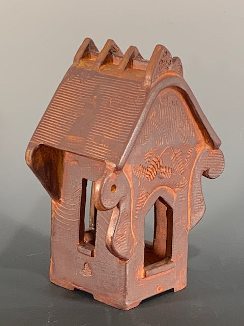Ceramic decorative house with intricate design on a gray background
