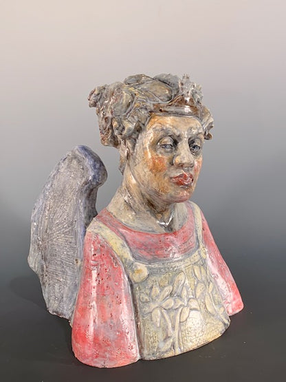 Decorative ceramic bust of person with wings on a gray background