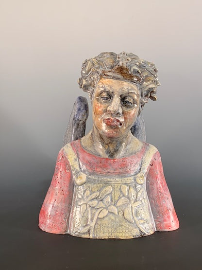 Decorative ceramic bust of person with wings on a gray background