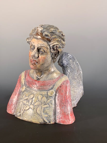 Decorative ceramic bust of person with wings on a gray background
