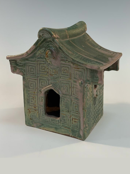 Green ceramic house with geometric patterns on a white background