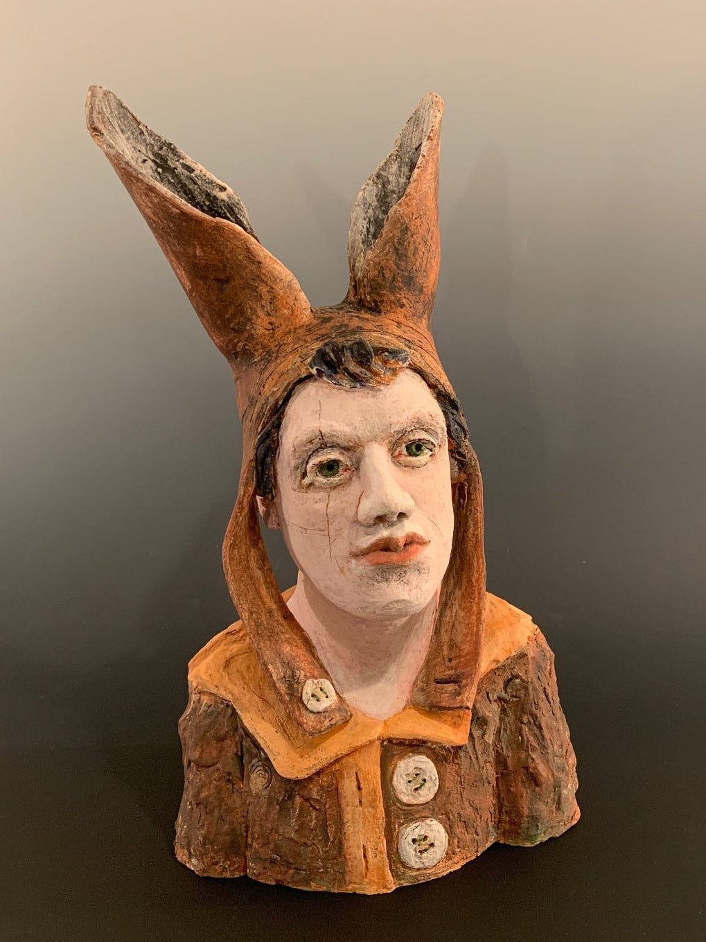 Ceramic figurine head with a face on a dark background