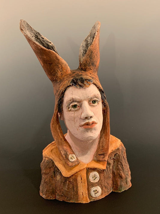 Ceramic figurine head with a face on a dark background