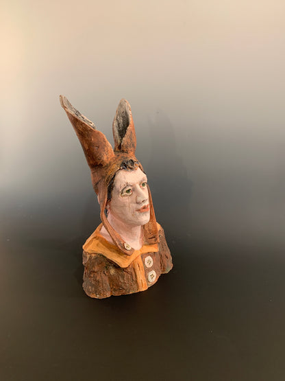 Ceramic figurine head with a face on a dark background