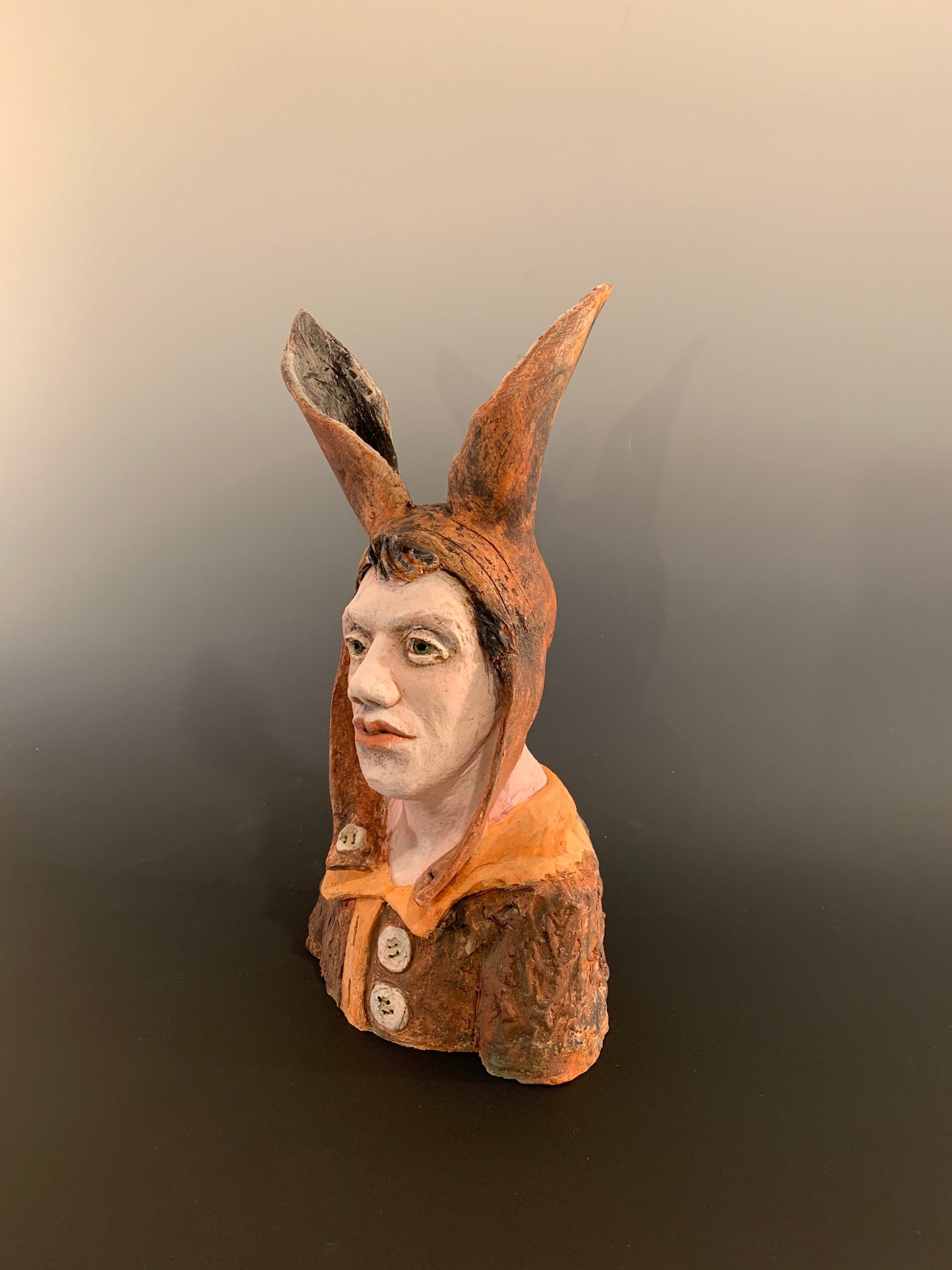 Ceramic figurine head with a face on a dark background
