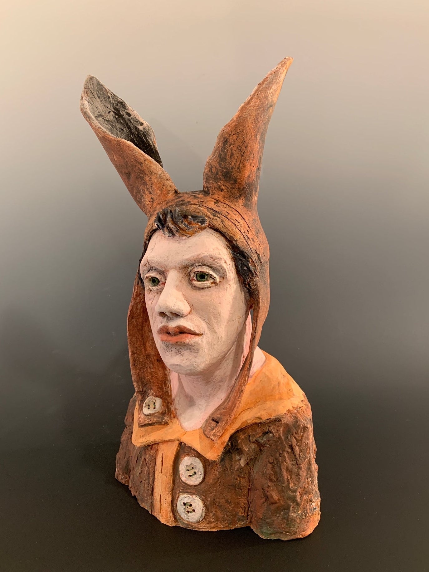 Ceramic figurine head with a face on a dark background
