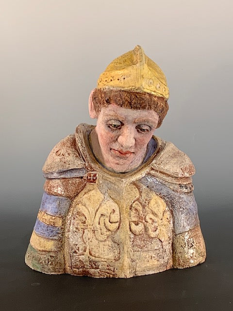 Decorative figurine of a person wearing a patterned garment and yellow hat on a gradient background