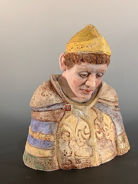 Decorative figurine of a person wearing a patterned garment and yellow hat on a gradient background