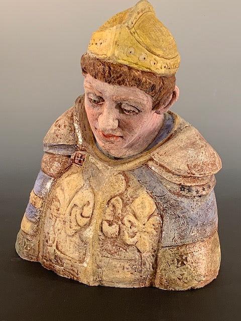 Decorative figurine of a person wearing a patterned garment and yellow hat on a gradient background