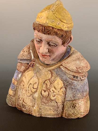Decorative figurine of a person wearing a patterned garment and yellow hat on a gradient background