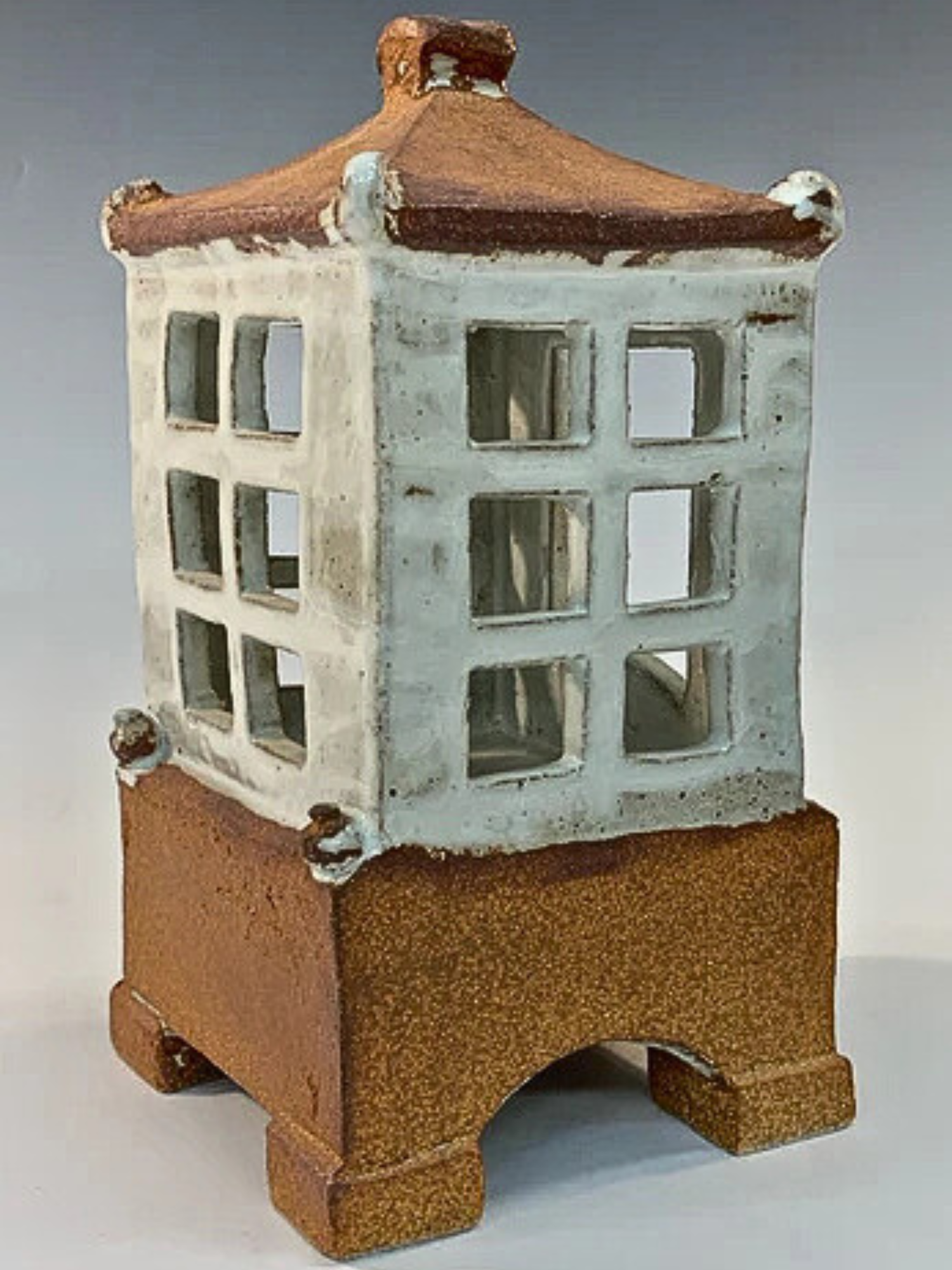 Ceramic house with a textured base and roof on a gray background