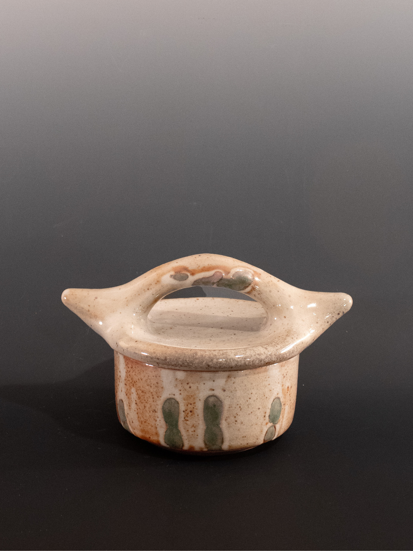 Small ceramic container with a lid on a dark background