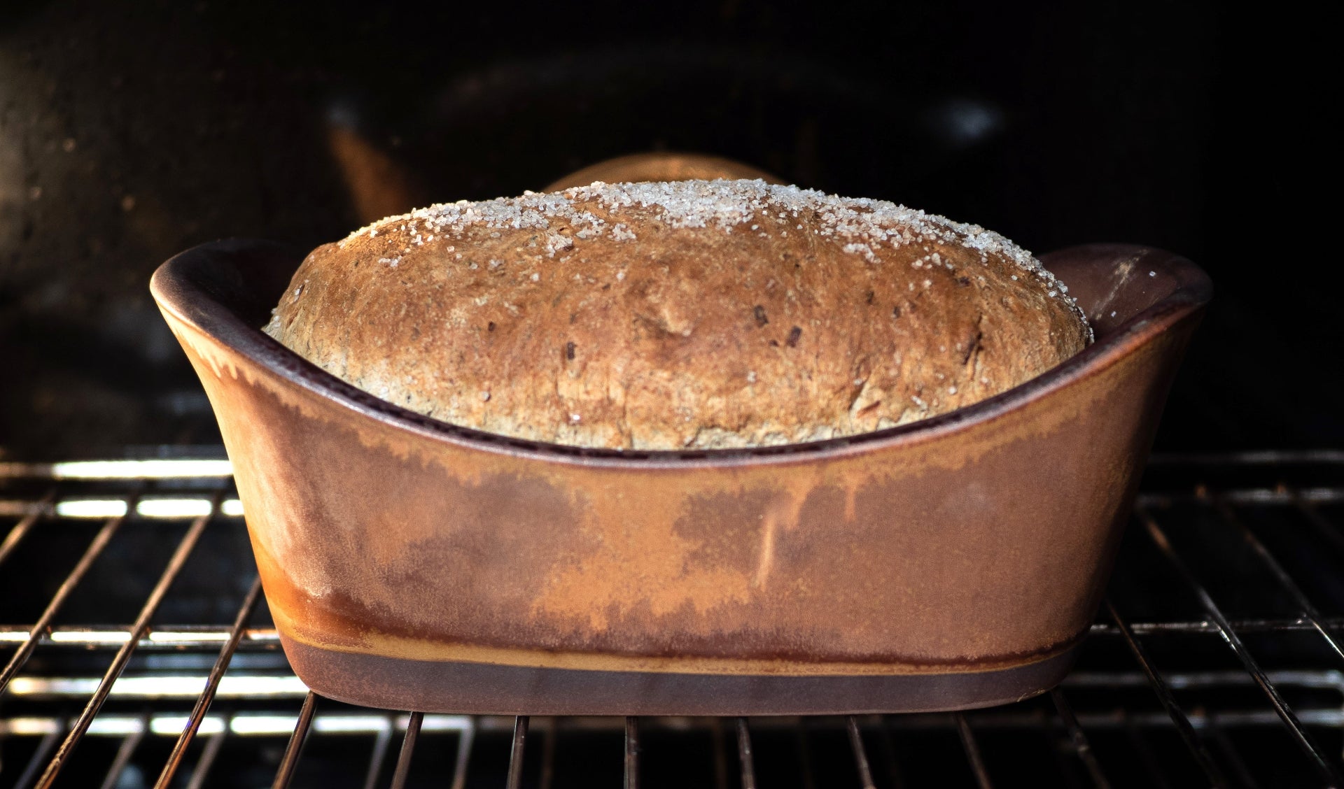 Loaf of bread in a ceramic baking dish inside an oven