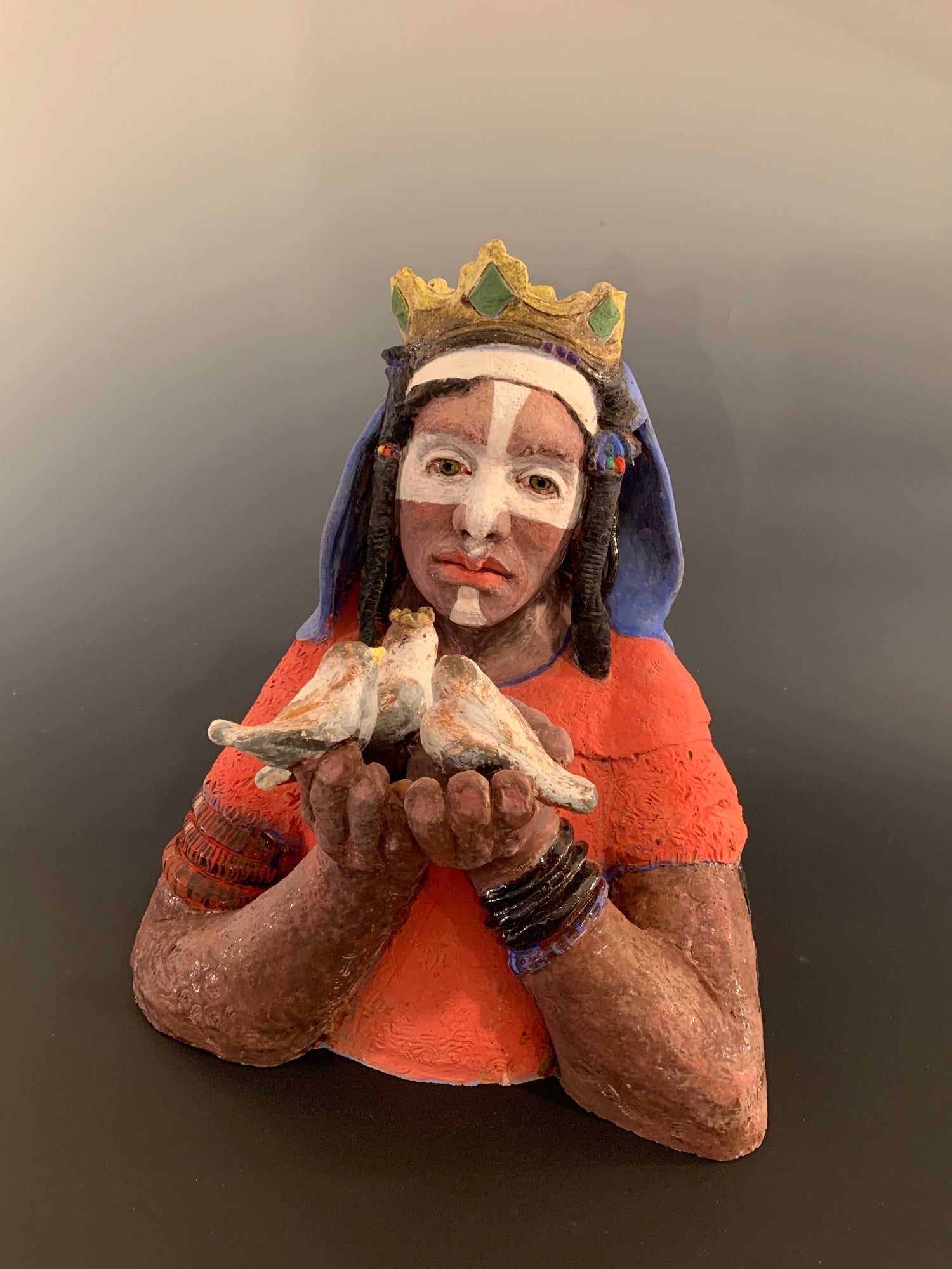 Traditional figurine with colorful attire and headdress on a plain background