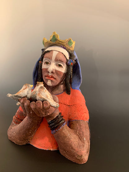 Ceramic figurine of a person holding birds against a gray background