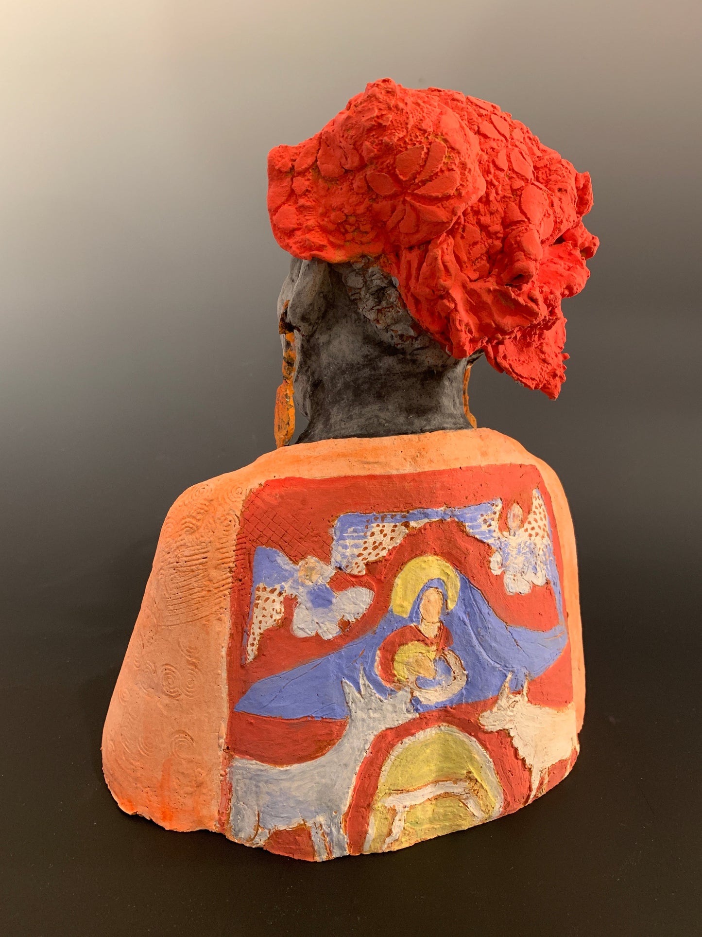 Small figurine of a person wearing an orange hood with floral details on a plain background