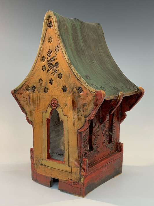 Decorative ceramic structure with a green roof on a white background