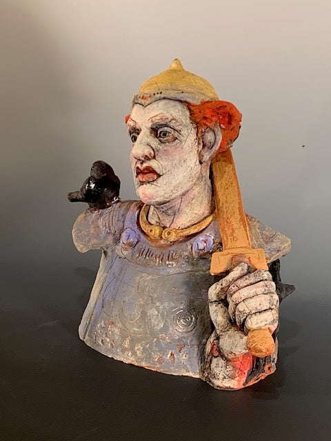 Ceramic bust with colorful face and clothing on a plain background